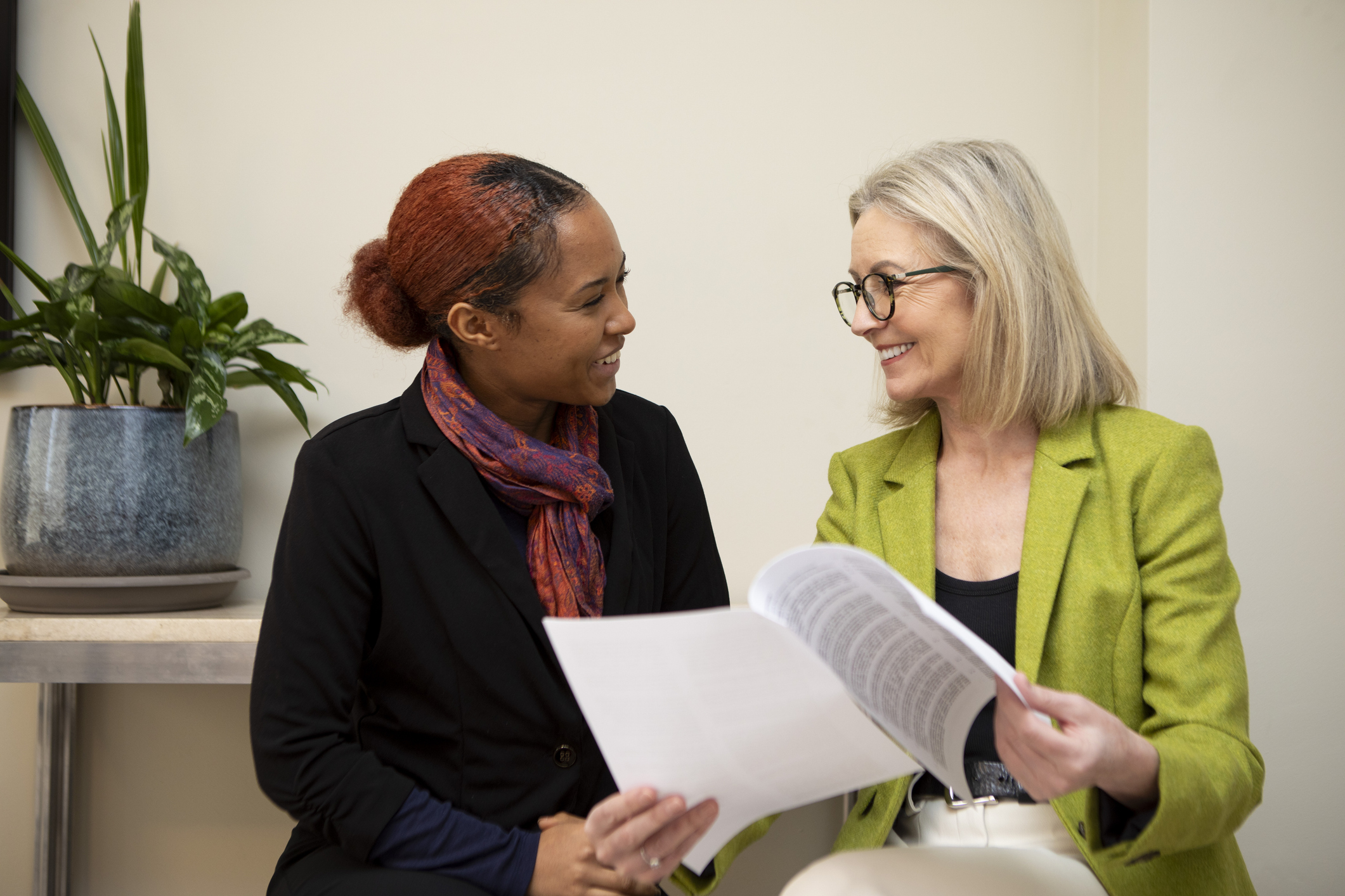 Two business colleagues sitting with paperwork and having a discussion